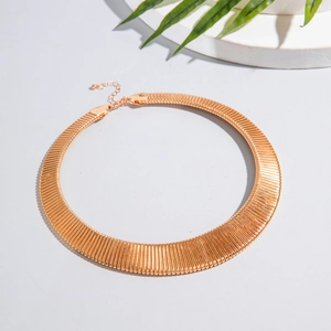 Flat lay of a bold gold textured choker necklace with ribbed patterns and lobster clasp