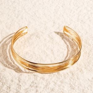 Macro view of multi-layered gold wire wrapped open cuff bracelet on stone background