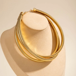 Detail of a three-layer gold collar necklace with ribbed texture and lobster clasp closure