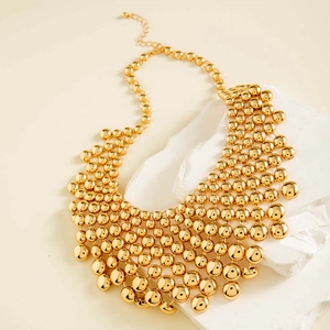 Detailed view of layered gold bead choker necklace on a white stone background