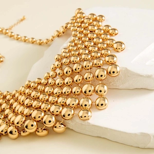 Macro shot of polished gold bead mesh necklace with elegant fringe detail and metallic sheen
