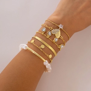 Detailed view of six-piece golden charm bracelet set with pearls and rhinestones on wrist