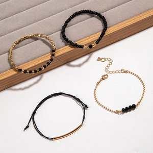 Ensemble de quatre bracelets faits main avec perles dorées et accents noirs sur velours gris
