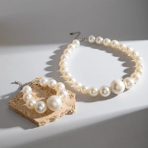 Detailed close-up of cream-white pearl jewelry set on a natural beige stone surface