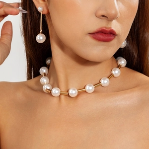 Detail of elegant pearl necklace with gold metal tubes and matching drop earrings on model