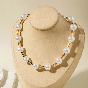 Detail of white pearls and polished gold cylindrical tubes on an elegant necklace