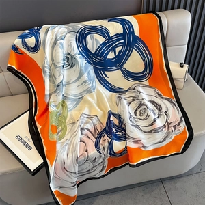 Detailed texture of silk scarf with orange borders and navy blue abstract floral pattern