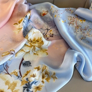 Detail of silk scarf with floral and butterfly patterns in soft pink and blue gradients