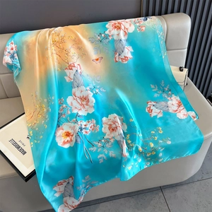 Detailed view of elegant silk scarf with floral patterns and butterflies draped on a sofa