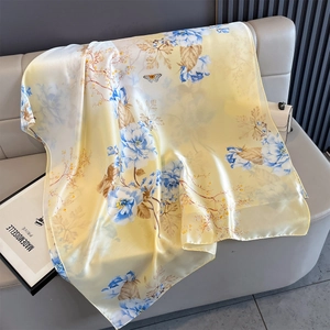 Close-up of silk-feel summer shawl with blue floral and butterfly prints on beige fabric