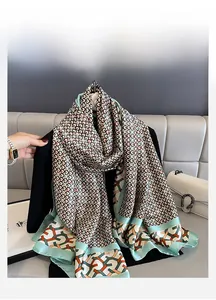 Detail of a silky summer scarf with geometric patterns in light green and orange