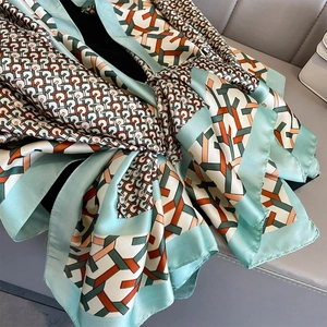 Detailed texture of lightweight silk scarf with mint green and orange geometric patterns