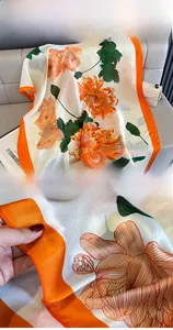 Close-up of elegant orange peony floral silk scarf showing fine edge stitching and texture