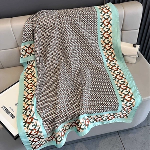 Detail of silk-like geometric chain print shawl with mint green border on a sofa