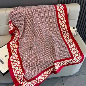 Detail of red geometric pattern silk shawl spread naturally on a grey sofa