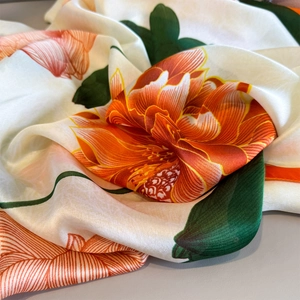 Detailed view of the silky satin scarf showing elegant orange peony print and pearly sheen