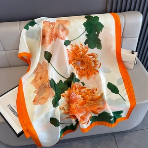 Detailed view of silk satin scarf featuring orange peony prints and elegant wide borders