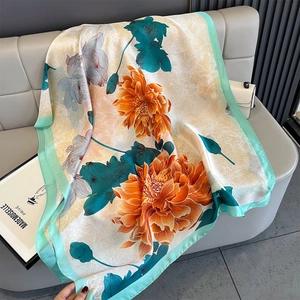 Detailed view of large satin peony floral scarf draped over a grey leather bench