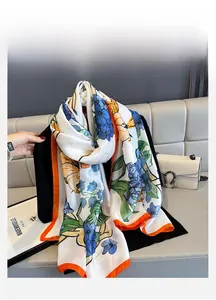 Close-up of elegant floral silk scarf with blue patterns and bright orange borders
