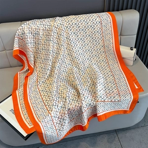 Detailansicht eines Seidenschals mit geometrischem Muster und orangenem Rand