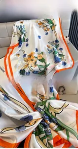 Detailed close-up of floral silk scarf with orange borders and elegant prints