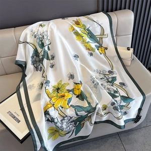 Detailed texture of printed silk scarf with yellow lilies and dark green border on sofa