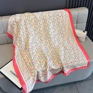 Nahaufnahme eines eleganten rosa-weißen Seidenschals mit geometrischem Muster auf Leder