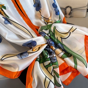 Silky satin floral long scarf with ivory base and orange borders tied on white handbag