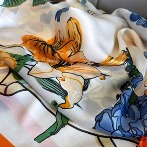 Lightweight ivory silk scarf with vibrant orange lily and blue floral prints and satin finish