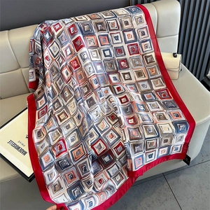 Detail of silk-like red shawl with colorful geometric abstract patterns on beige leather