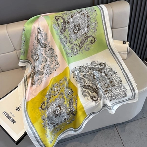 Close-up of silk-satin scarf featuring color-block paisley patterns on a sofa