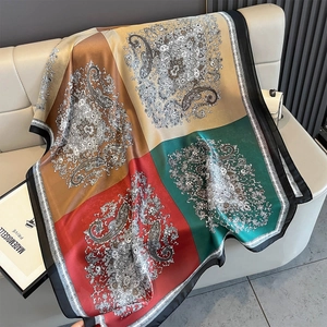 Detail of silk satin scarf with paisley prints and color-block design on leather sofa