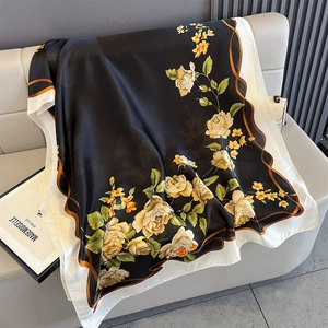 Detail showing elegant black satin silk scarf with yellow rose print on leather sofa
