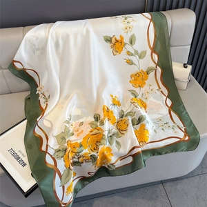 Detailed texture of a silky floral shawl with yellow roses and green borders on a sofa