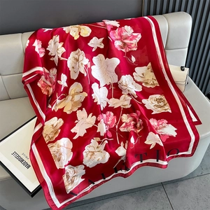 Detail of red floral silk scarf with vintage flower patterns on grey leather sofa