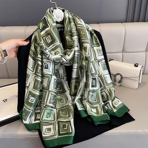 Long silk scarf with green and white geometric pattern over a black suit jacket
