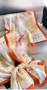 Detail shot of feather print silk scarf with vibrant orange edges and soft texture