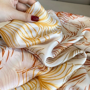 Macro shot of breathable summer shawl fabric with silky texture and orange feather print