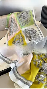 Detailed view of silk scarf fabric with paisley patterns and precise edge stitching