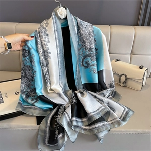 Classic silk-textured shawl featuring blue and black paisley print draped on a leather sofa