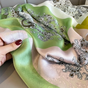 Detailed view of paisley silk scarf with satin finish and elegant green color blocking
