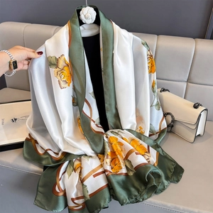 Elegant floral silk shawl with green border displayed on a decorative hanger