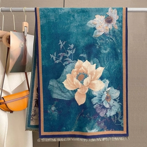 Elegant teal oversized shawl with lotus print and orange accents on a metal rack