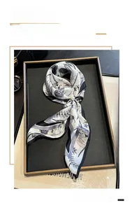 Close-up of silk scarf with dragonfly print and pearl ring on a luxury jewelry tray