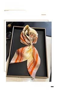Détail d'un foulard en soie à motif paisley avec boucle en perle sur un plateau