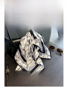 Detail of dragonfly silk scarf tied to a black handbag with luxury accessories