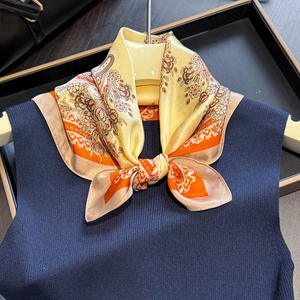Foulard en soie à fleurs jaune et orange noué sur un pull en tricot bleu marine