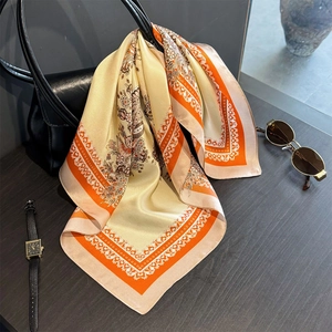 Élégant foulard en soie à imprimé floral noué sur l'anse d'un sac à main noir