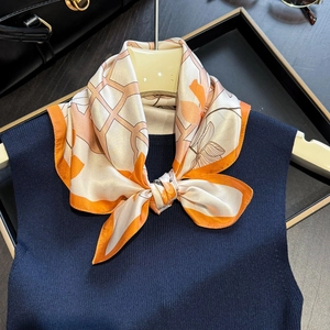 Elegant orange and beige silk scarf with floral patterns on a dark navy knit background
