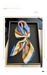Detail of silk square scarf with blue and gold floral patterns and a pearl accessory
